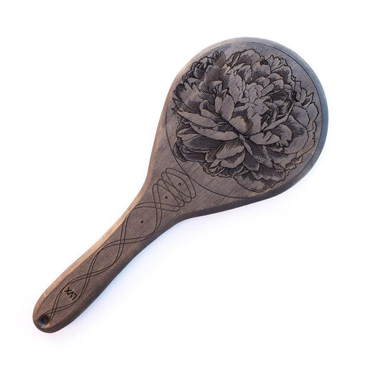 The Ebony Pine Peony Engraved Wooden Spanking Paddle, a dark wood ping-pong style panel with a detailed peony engraved on it, is displayed against a blank background.