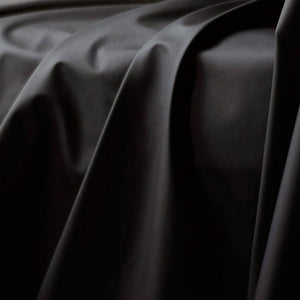 A close-up of the Fluid Proof Protective Throw By Sheets Of San Francisco is shown, displaying the drape and folds of the fabric.