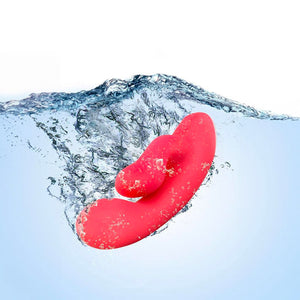 The Cerise Hop Trix Rabbit Vibrator is shown submerged in clear blue water.