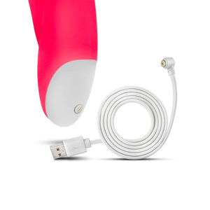 A close-up of the base of the Cerise Hop Trix Rabbit Vibrator is shown with its charger next to it against a blank background.