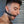 Load image into Gallery viewer, A close-up of a dark-haired man’s face is shown. He has some facial stubble and is wearing a metal hoop earring. He stands in front of a metal wall, looking down, and is wearing the Silicone O-Ring Bondage Mouth Gag.
