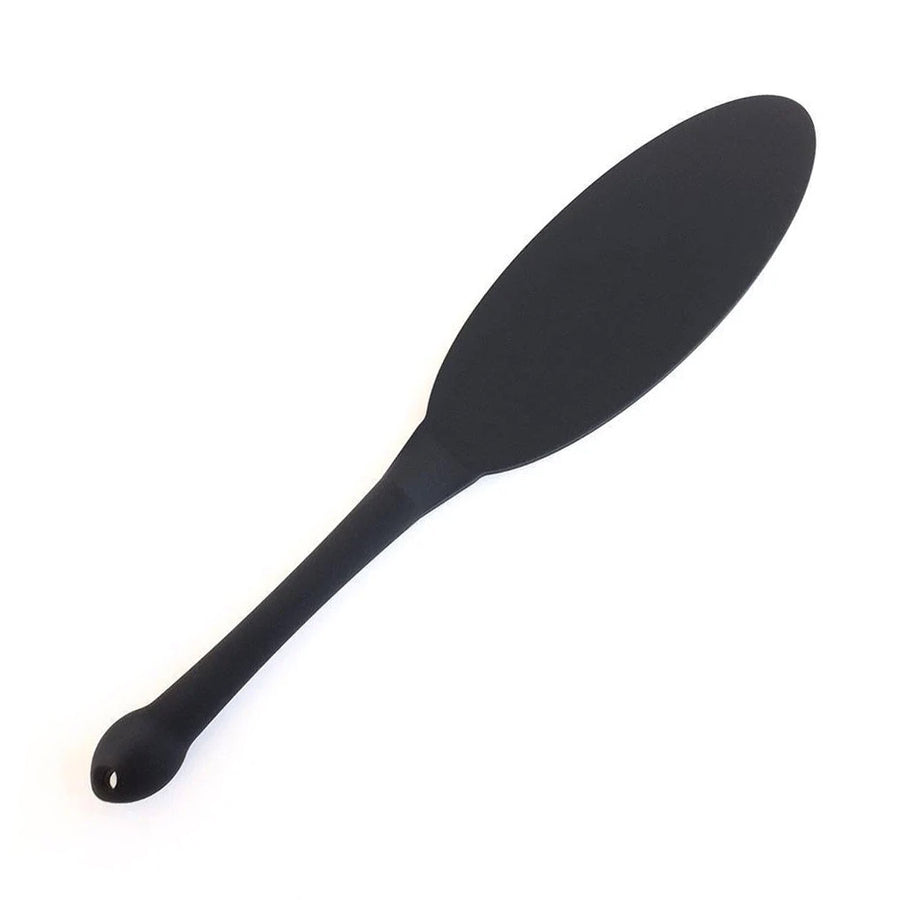 The matte black Tantus Gen Mini Silicone Paddle is displayed against a blank background. The top of the paddle is thin and oval in shape, and the handle is cylindrical with a bulbous bottom.