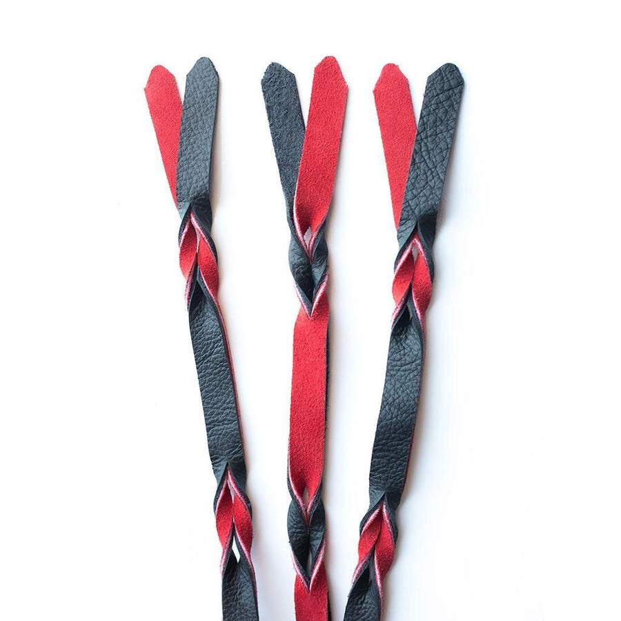 A close-up of the falls on the red and black Braided Leather Flogger is displayed against a blank background.