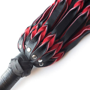 A close-up of the top of the red and black Braided Leather Flogger handle is displayed against a blank background.