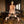 Load image into Gallery viewer, A nude blonde woman is shown kneeling on a leather bench, facing away from the camera. The bench is placed in front of a dining table. Her wrists and ankles are locked in the black leather cuffs of the Deluxe Pranger Pillory 4-Point Spreader Bar.
