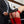 Load image into Gallery viewer, A close-up of a woman’s ass is shown. She is bent over and wears red latex panties, a garter, and stockings. A man in a navy suit stands next to her, holding the Daddy&#39;s Belt slapper against her ass.
