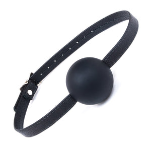 The black Silicone Ball Gag With A Garment Leather Strap is displayed against a blank background. It is a medium-sized black ball made of matte silicone with a thin, adjustable black leather strap.