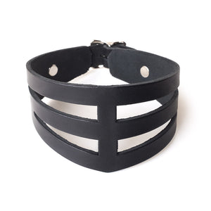 The STK Lux “Dom” Collar is shown against a blank background. The collar is made from black leather and is shaped like a V.