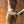 Load image into Gallery viewer, A nude person’s torso and thighs are shown from the back as they stand against a brick wall. A gloved hand is bringing the Leather Wrapped Wood Spanking Paddle down to spank their ass.
