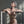 Load image into Gallery viewer, A nude woman with short, silver hair poses in front of a metal wall, her arms resting on a metal railing. She wears the Clear CTRL Bust Harness and a matching Clear CTRL waist and wrist cuffs.

