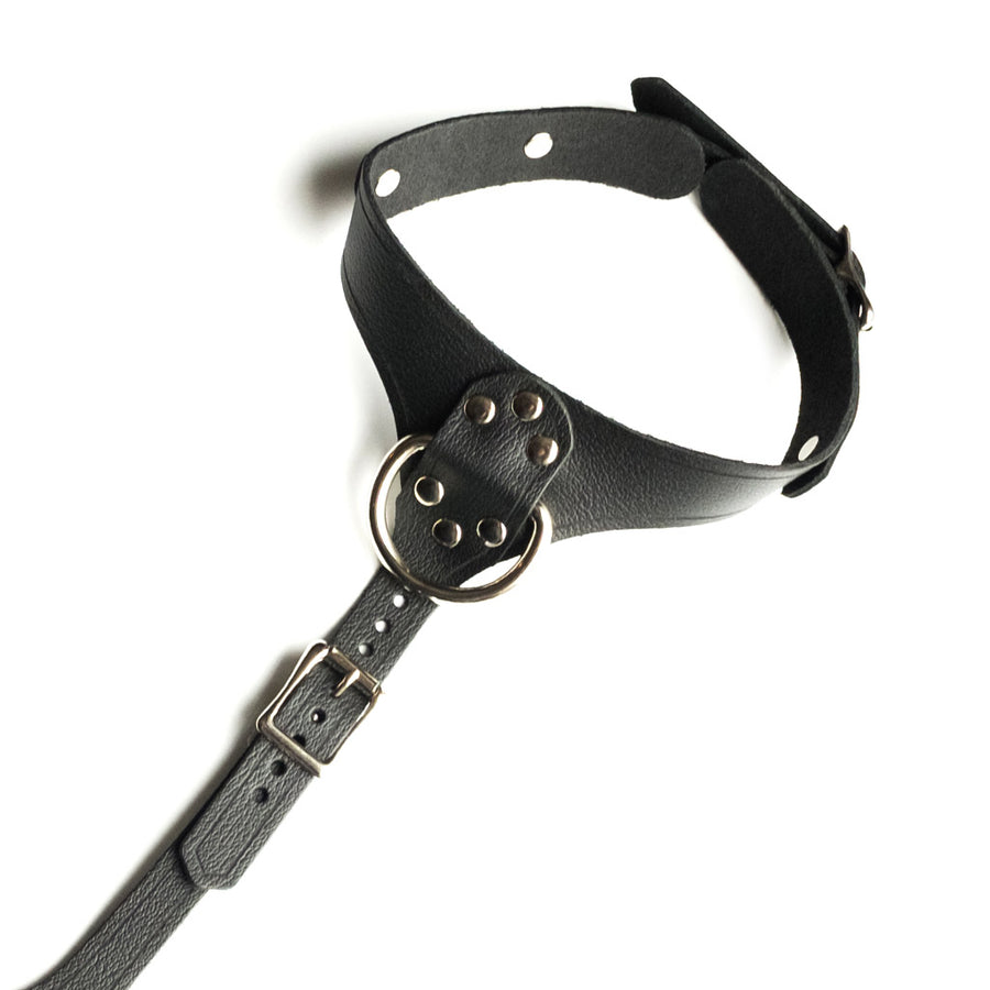 A close-up of the neck portion of the Full Curves Leather Bust Harness is shown against a blank background. It is made of black leather with silver hardware. There is a D-ring in the center of the collar and an adjustable strap beneath it.
