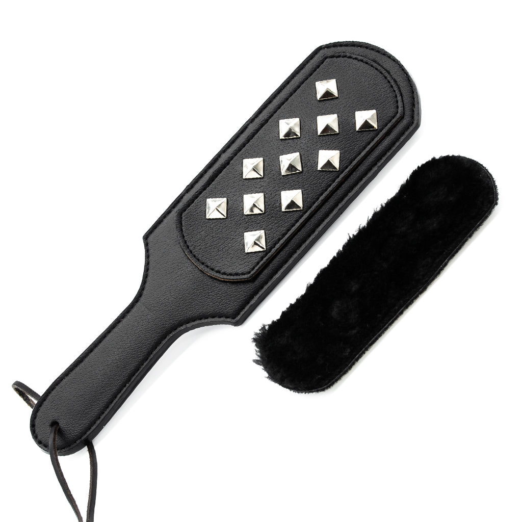 The Kinklab Panamorphic Paddle 3-In-1 Spanking Set is displayed against a blank background. The black rectangular paddle has the metal stud attachment on it, and the faux fur attachment is show next to it.
