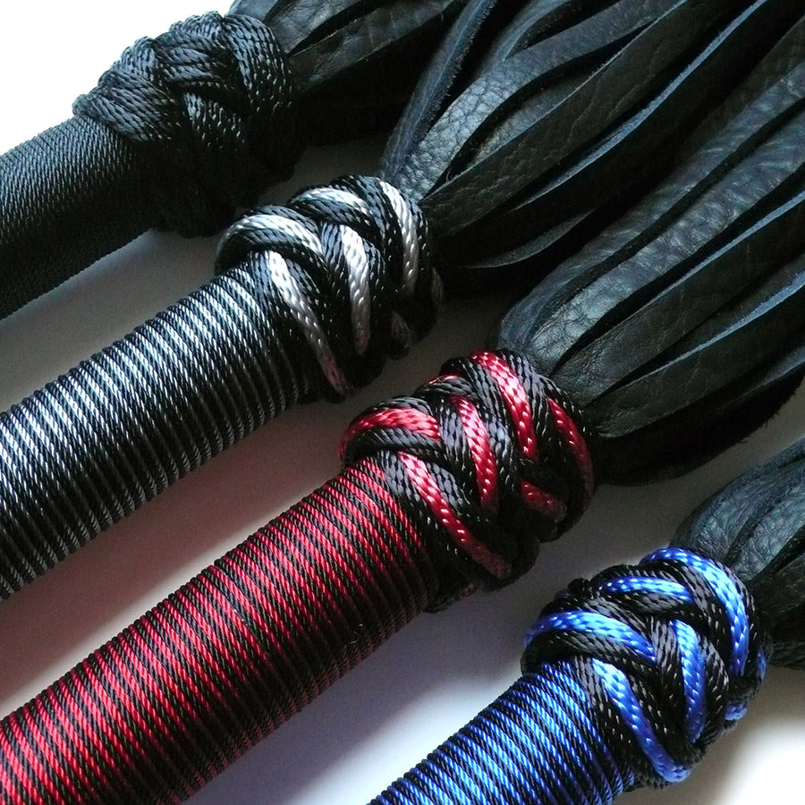 A close-up of the tops of the handles of the 30-inch Elk Hide Floggers in every color is displayed against a blank background.