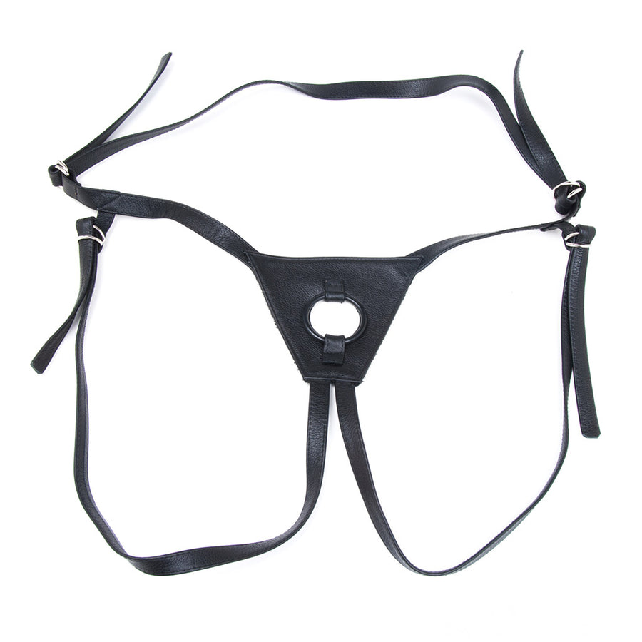 The black leather Texas Two-Strap strap-on harness is displayed against a blank background. The harness has a waist strap and two leg straps, all of which are looped through small D-rings.