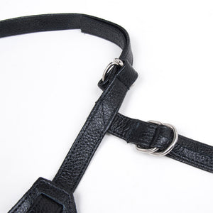 A close-up of the straps on the Terra Firma Dee black Leather Strap-on Harness is displayed against a blank background. There are metal D-rings on the straps.