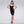 Load image into Gallery viewer, A woman with black hair and red lipstick poses in front of a grey backdrop. She wears the Newmar Latex Dress by Syren Latex in black. The dress has thin camisole straps and a neckline that outlines her bust. The hem ends right above her knee. 
