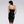 Load image into Gallery viewer, A woman with black hair and red lipstick poses in front of a grey backdrop, turned away from the camera. She wears the Newmar Latex Dress by Syren Latex in black, which has a zipper in the back.
