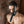 Load image into Gallery viewer, A shirtless man stands beside a brick wall wearing the black leather Head-On Gag Harness. A piece of leather holding a black dildo covers his mouth. The harness straps around the back of his head and over his face.
