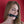 Load image into Gallery viewer, A close-up of a woman with dirty blonde hair standing in front of a red wall shows her with the black Silicone Bone Gag With a Silicone Strap in her mouth. 
