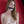 Load image into Gallery viewer, A topless woman with dirty blonde hair stands in front of a red wall with the black Silicone Bone Gag With a Silicone Strap in her mouth.
