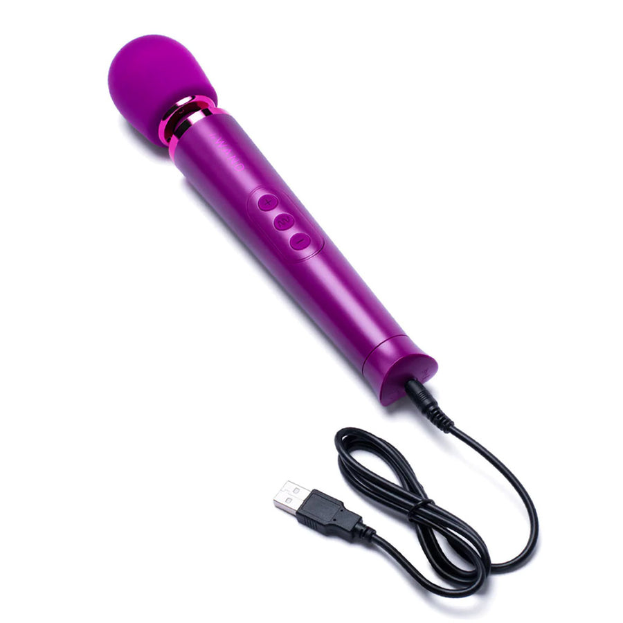 A Le Wand Petite Rechargeable Vibrating Massager in Dark Cherry is shown against a blank background with its charging cord plugged into it.