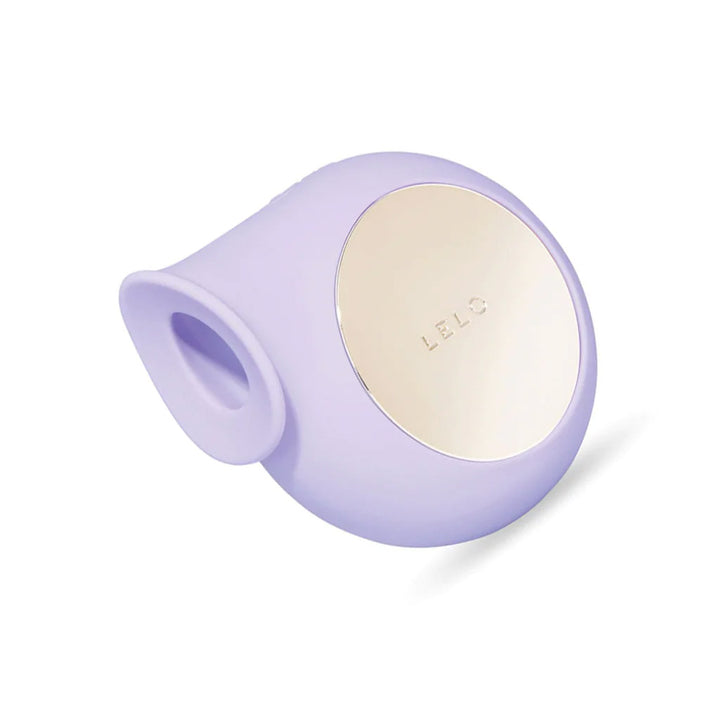 The Lelo Sila Cruise Clitoral Massager Vibrator in Lilac is shown against a blank background. The toy is circular, with a gold circle in center. One part of the circle is flattened and projected slightly with a hole in the projection for the clitoris.