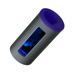 The Lelo F1S V2X Vibrating Masturbator in blue is shown against a blank background. The toy is cylindrical with a grey outside and a blue cap on one end. There is a window to the inside of the toy, which is dark blue.
