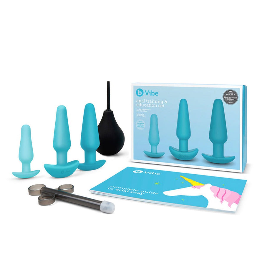 The contents of the b-Vibe Anal Training & Education Butt Plug Set in Aqua are shown against a blank background. The box is shown along with the 3 plugs, a black enema bulb and lube shooter, and a guide to anal play.