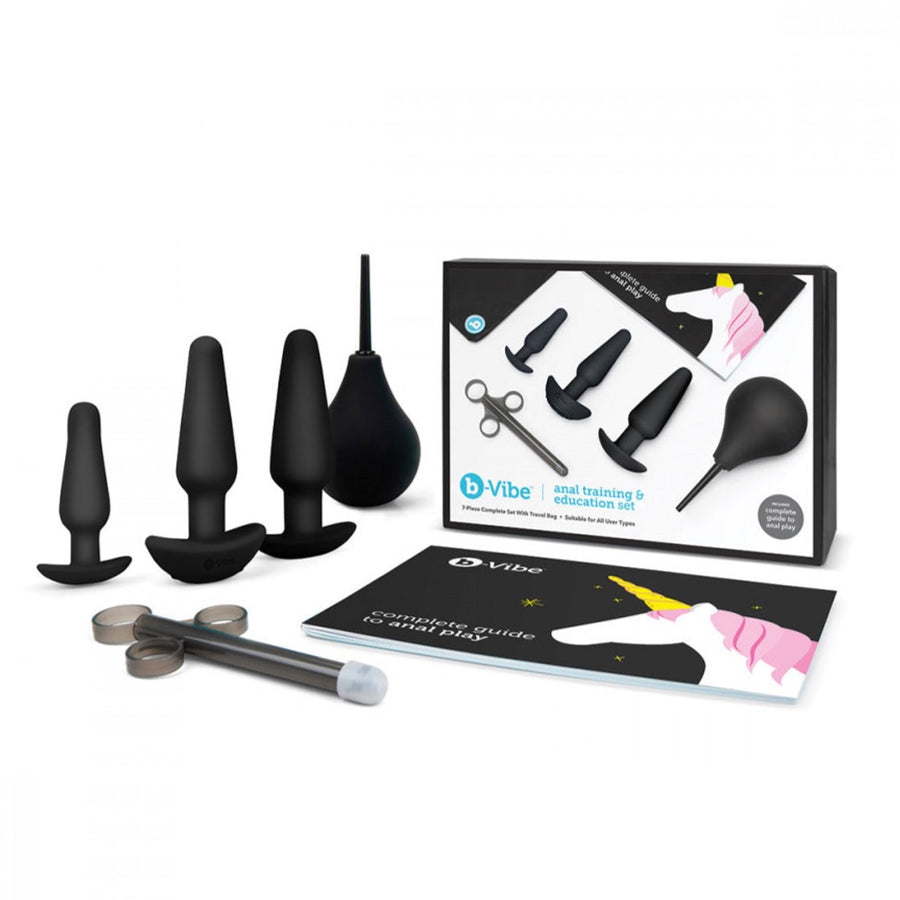 The contents of the b-Vibe Anal Training & Education Butt Plug Set in Black are shown against a blank background. The box is shown along with the 3 plugs, a black enema bulb and lube shooter, and a guide to anal play.