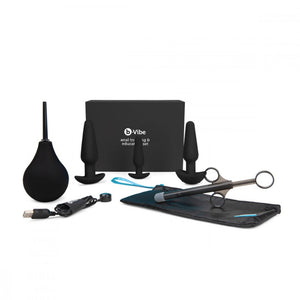 The contents of the b-Vibe Anal Training & Education Butt Plug Set in Black are shown against a blank background. The 3 plugs are shown with a black enema bulb and lube shooter, a black cloth case, and a charger.