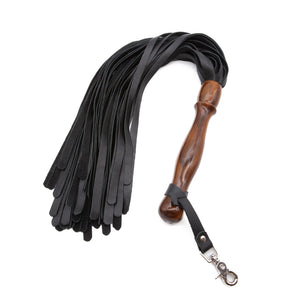 The Sissoo Rosewood Long Handle Leather Flogger is shown on a white background. Attached to the flogger is the included leather hanger strap with crab-claw hook. The BDSM impact play toy features leather falls and a wooden round handle.