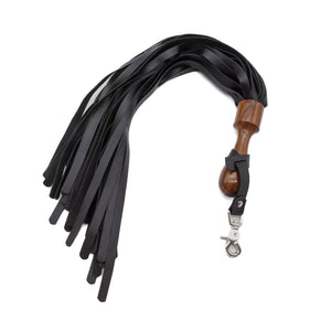 The Sissoo Rosewood Short Round Handle Leather Flogger is shown on a white background. Attached to the flogger is the included leather hanger strap with crab-claw hook. The BDSM impact play toy features leather falls and a wooden round handle.