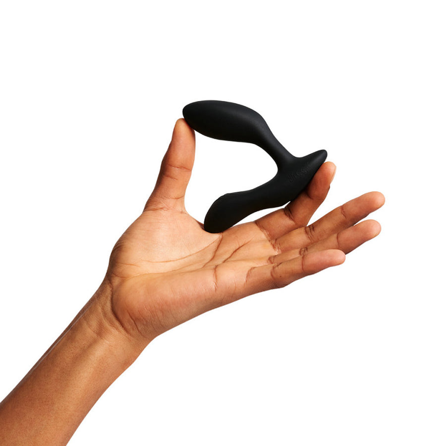 The We-Vibe Vector+ Vibrating Prostate Massager is shown with a hand holding it on a white background.