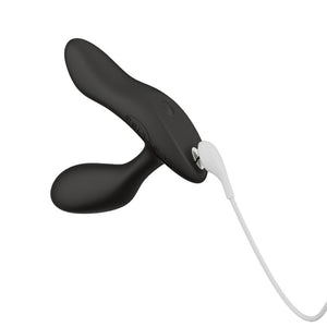 The We-Vibe Vector+ Vibrating Prostate Massager is shown with the included charger attached to it on a white background.