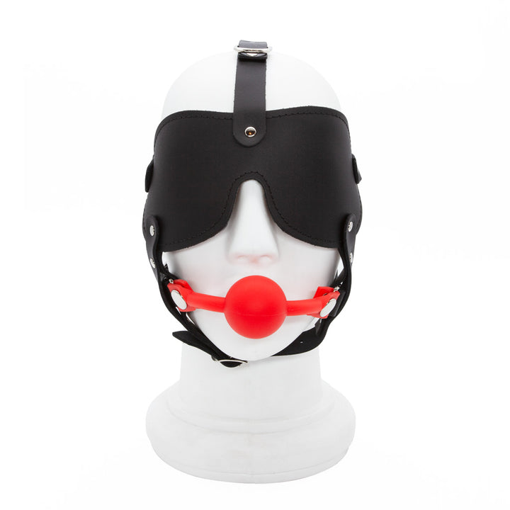 The Silicone Ball Gag And Blindfold Head Harness is displayed on a mannequin head against a blank background. The harness is made of black leather, with a blindfold and straps over the head and under the chin. 