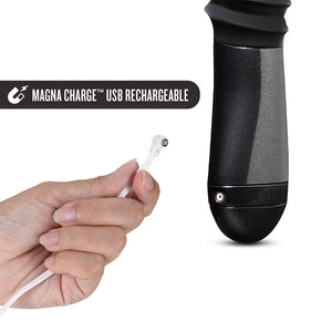An image of the Temptasia Lazarus Thrusting Rechargeable Vibrating Dildo in Black by Blush Novelties on a plain white background. It is next to a hand holding the included charging cord.