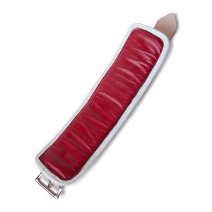 One of the Deluxe Padded Medical Leather BDSM Wrist Restraints is shown lying flat against a blank background, displaying the inside of the cuff. The cuff is lined with red leather with a white border. 