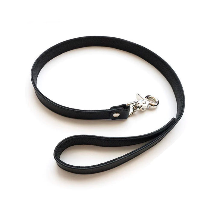 The black BDSM 2.5' Premium Garment Leather Leash is shown against a blank background. The leash is made of a strip of black garment leather looped into a handle on one end and with a metal snap hook on the other.