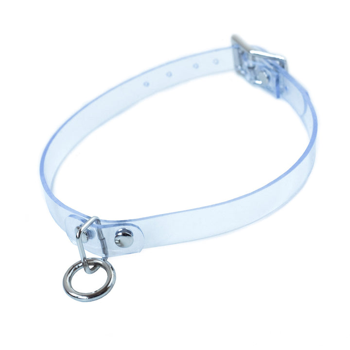 The Clear CTRL Vinyl Choker is shown against a blank background. It is a thin piece of transparent PVC with silver hardware. It has a dangling O-ring in the center and an adjustable strap with a buckle.