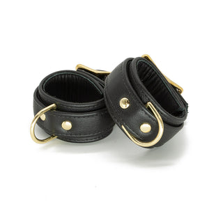 A pair of black Garment Leather Wrist Cuffs With Brass Gold Hardware are shown buckled against a blank background.