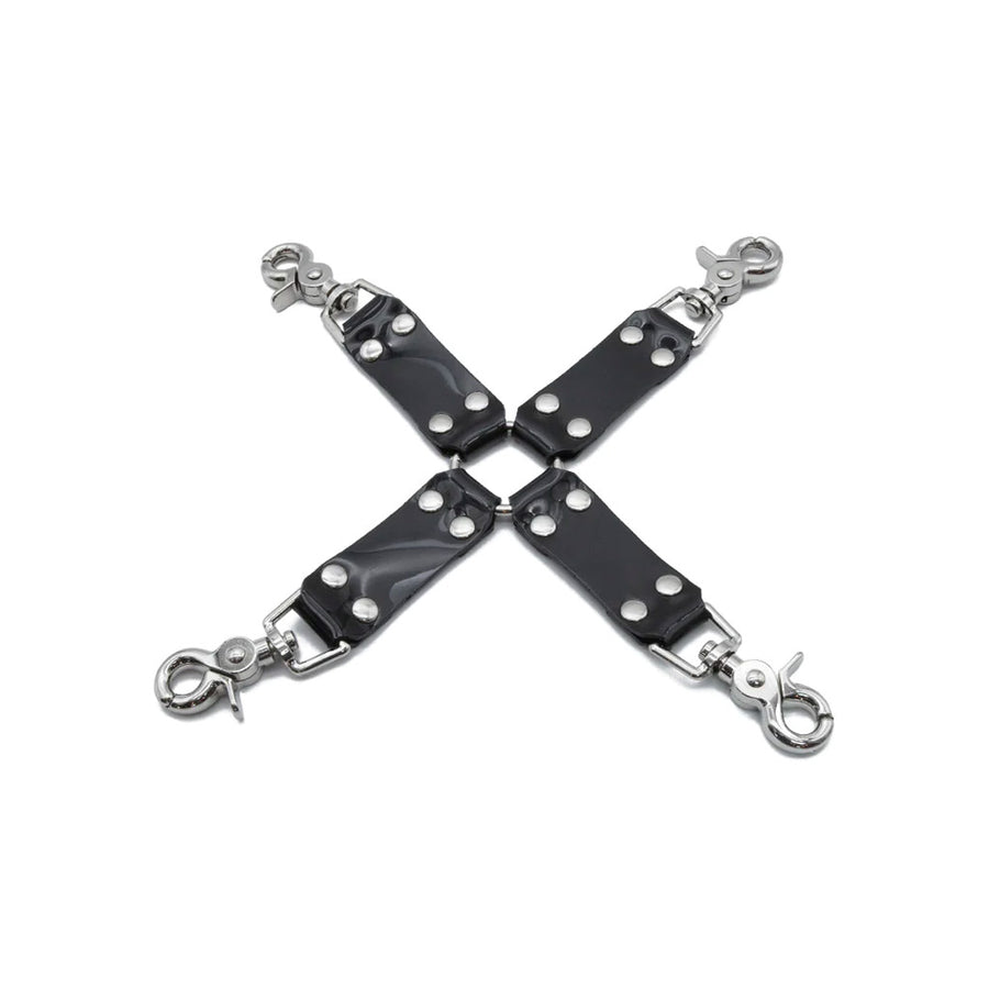 The front of the Stockroom Black PVC Hog Tie is shown against a blank background. The hog tie is X shaped with four strips of black PVC connected to a silver O-ring in the middle. Each strip of PVC has a snap-hook attached at the end.