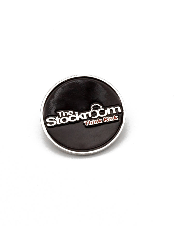  The Stockroom Enamel Pin is shown against a blank background. The pin is circular and has a black background with The Stockroom logo on it and the slogan “Think Kink” underneath.