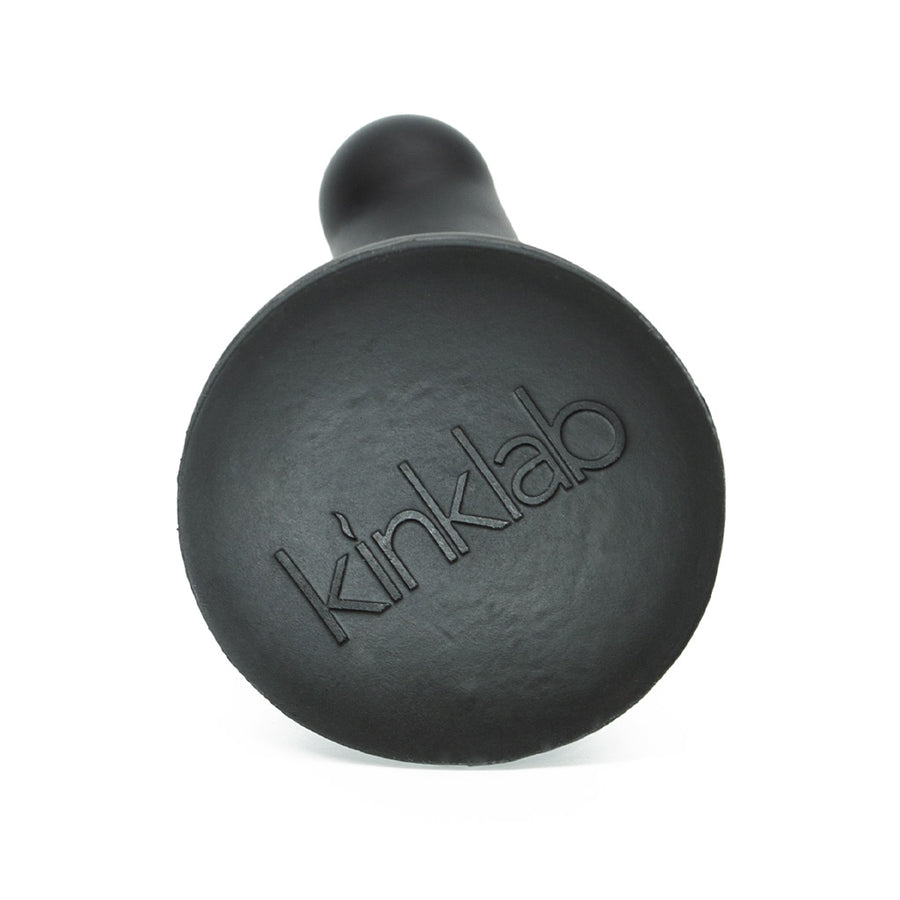 The base of the KinkLab Ebb & Flow Silicone Dildo in black is shown against a blank background. It has the KinkLab logo embossed on it.