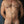 Load image into Gallery viewer, A muscular nude man’s torso and thighs are shown in front of a metal wall. He wears the Nipple Clamps/Cock Ring Set with the cock ring behind his balls. 
