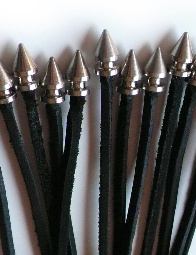 A close-up of the tips of the falls of the black leather 20-inch Thong Whip with Spiked Tails is displayed against a blank background.