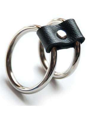 The Double-O Cock Ring, made of two silver metal cock rings lined up next to each other and connected by a small piece of black leather, is displayed against a blank background.