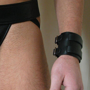 A close-up of a man's wrist is shown. He is wearing the 2-Strap black Leather Wrist Band.