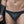 Load image into Gallery viewer, A close-up of a man&#39;s torso and thighs is shown. He wears the black Neoprene Thong, which has metal O-rings connecting the thong to black elastic hip straps. He is also wearing black leather lace-up arm gauntlets.
