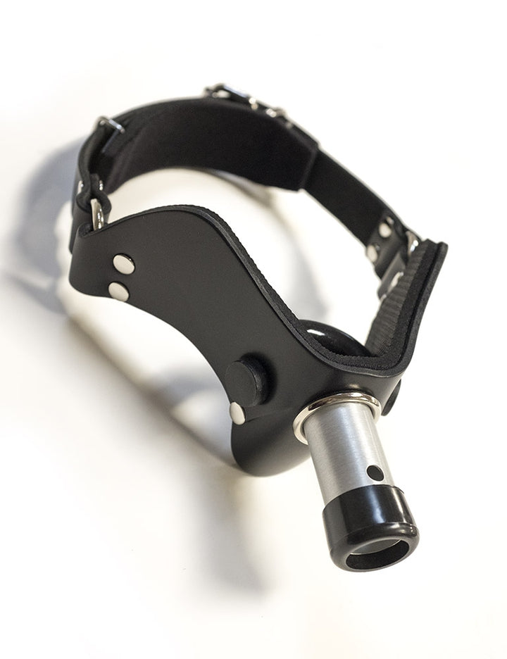 The “How May I Help You?” Gag, A.K.A the Humiliator Gag, is displayed against a blank background. The gag has a padded, black leather V-shaped front with a rounded bit on the inside. A short metal rod protrudes from the center of the gag.  