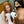 Load image into Gallery viewer, Two nude women pose in a bathroom. The brunette, wearing the “How May I Help You?” Gag with a toilet paper roll attachment with toilet paper, kneels next to the toilet. The red-haired woman sits on the toilet, grabbing toilet paper from the gag.
